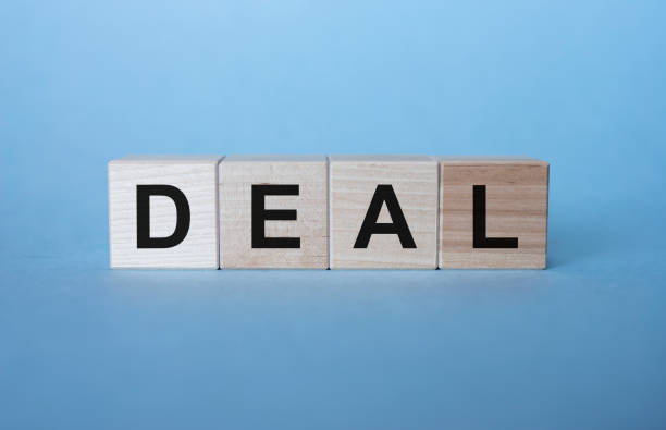istock DEAL word on cube blocks on blue background 1220413983