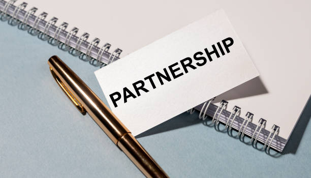 istock Partnership word on white sticker with golden pen and white notepad on grey blue background. Business concept 1220413999