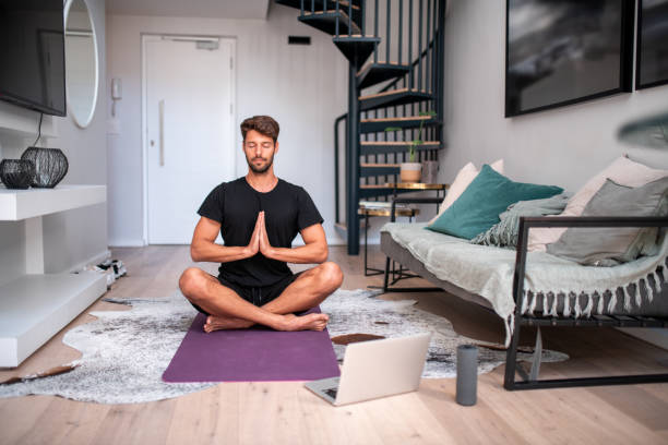 istock Young man meditating in the living room. 1220414292