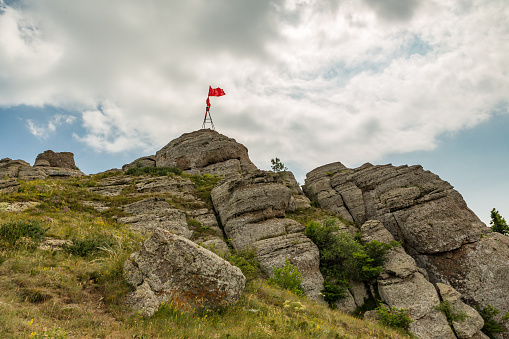 Mount Demerdzhi (Demirji Yayla) in Crimea, natural landscape, travel. Red flag at the top
