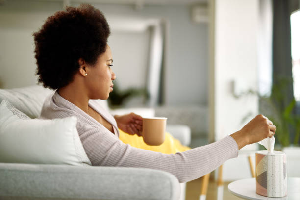 istock Black woman taking tissue from a box while resting in the living room. 1220418193