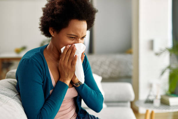 istock Black woman using tissue while blowing nose at home. 1220418758
