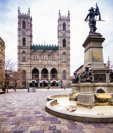 Montreal Notre-Dame cathedral with Maisonneuve Monument in the foreground, photographed at Place d'armes. This monument was erected in 1895.