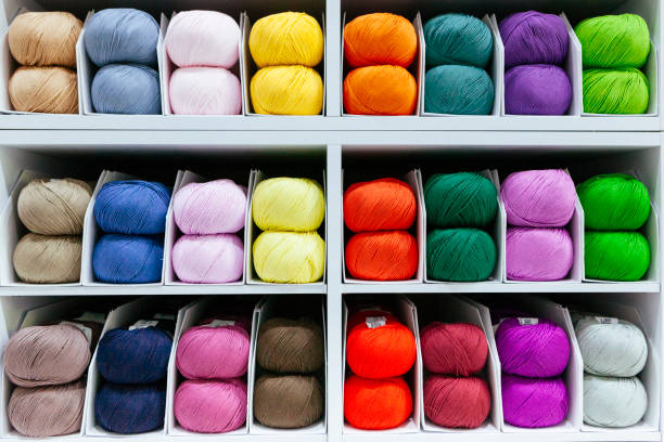 pattern of colorful different wools yarns organized by color with creativity on a white shelf