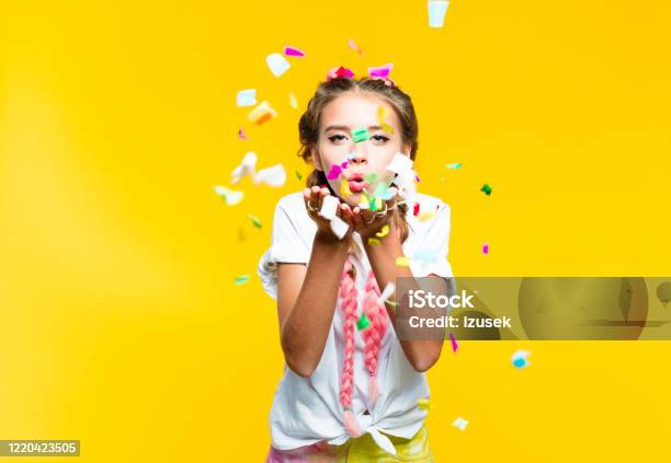 Teenage Girl Blowing Colorful Confetti Stock Photo - Download Image Now - Confetti, Child, Yellow Background