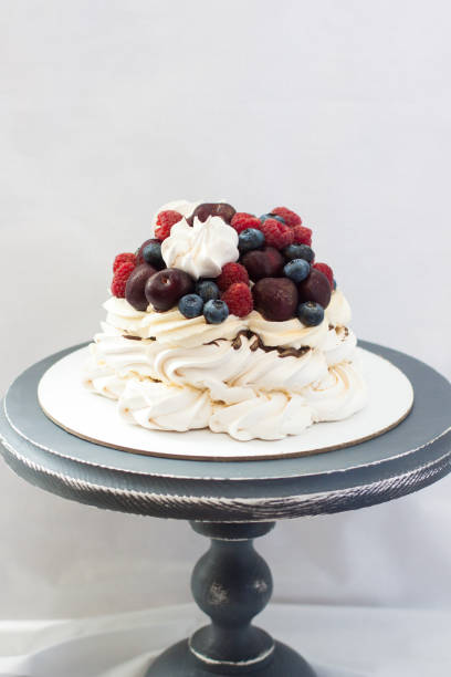 Meringue Pavlova cake with chocolate sauce, whipped cream and fresh cherries, strawberries, blueberries.
