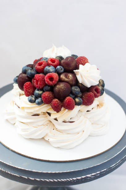 Meringue Pavlova cake with chocolate sauce, whipped cream and fresh cherries, strawberries, blueberries.