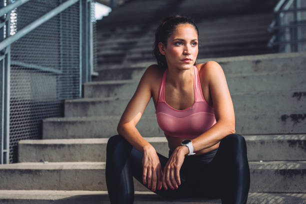 portrait of a beautiful woman athlete in sportswear sitting on stairs to rest - determination running staircase jogging imagens e fotografias de stock