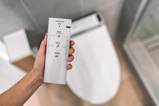 Smart japanese bidet automated toilet washlet with remote for easing cleaning rinsing with water without using toilet paper. at home bathroom modern lifestyle.