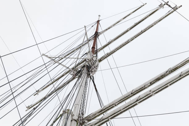 Masts and yards of an old sailing ship are under white winter sky. Sailing equipment