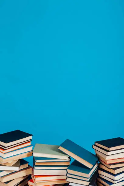 Photo of a lot of stacks of educational books in the college library on a blue background
