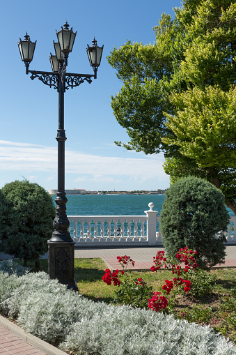 A lantern in a classic style by a flowerbed on the city's waterfront