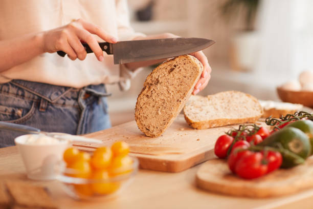 istock Woman Cutting Bread Close Up 1220430589