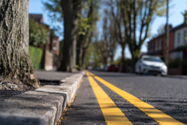 Close up of double yellow lines at the curb of a residential street Close up of double yellow lines (meaning, no parking at any time) at the curb of a tree lined residential urban street, Belfast, Northern Ireland. curb photos stock pictures, royalty-free photos & images