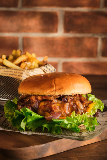 istock Burger with beef and caramelized onions on a wooden board. Cheeseburger with onion and beef. Juicy Delicious Homemade Burger. 1220432161
