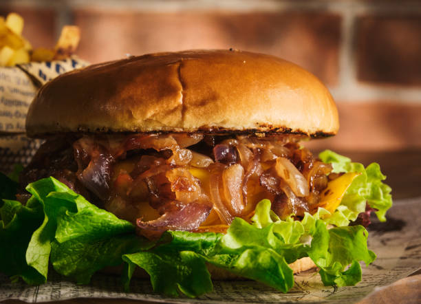 istock Burger with beef and caramelized onions on a wooden board. Cheeseburger with onion and beef. Juicy Delicious Homemade Burger. 1220433113