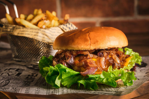 istock Burger with beef and caramelized onions on a wooden board. Cheeseburger with onion and beef. Juicy Delicious Homemade Burger. 1220434116