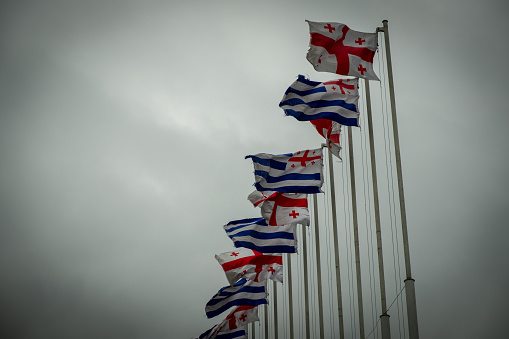 Flags of the state of Georgia on tall posts. Flagpoles on the street. Day Cloudy.