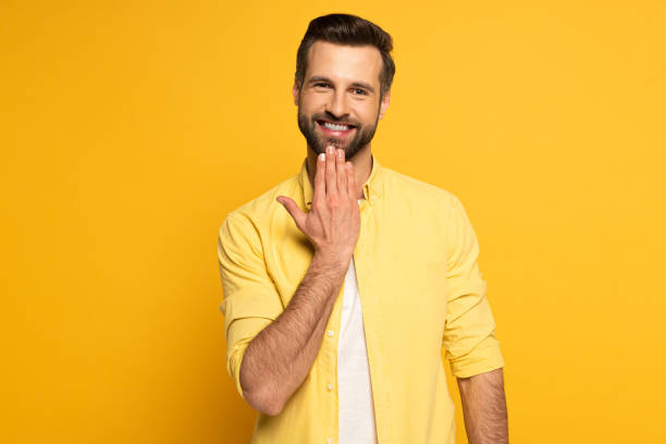 Smiling man looking at camera while showing word speak in sign language on yellow background Smiling man looking at camera while showing word speak in sign language on yellow background sign language stock pictures, royalty-free photos & images