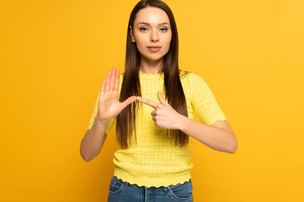 istock Attractive girl using sign in sign language language on yellow background 1220435849