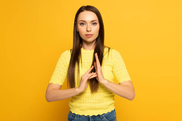 istock Young woman showing gesture while using sign language language on yellow background 1220435858