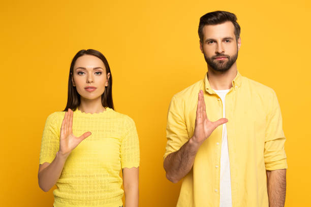 istock Young couple showing gesture in sign language on yellow background 1220435874
