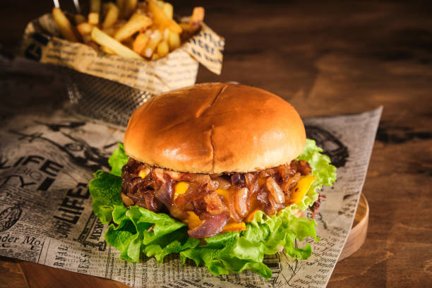 istock Burger with beef and caramelized onions on a wooden board. Cheeseburger with onion and beef. Juicy Delicious Homemade Burger. 1220436457