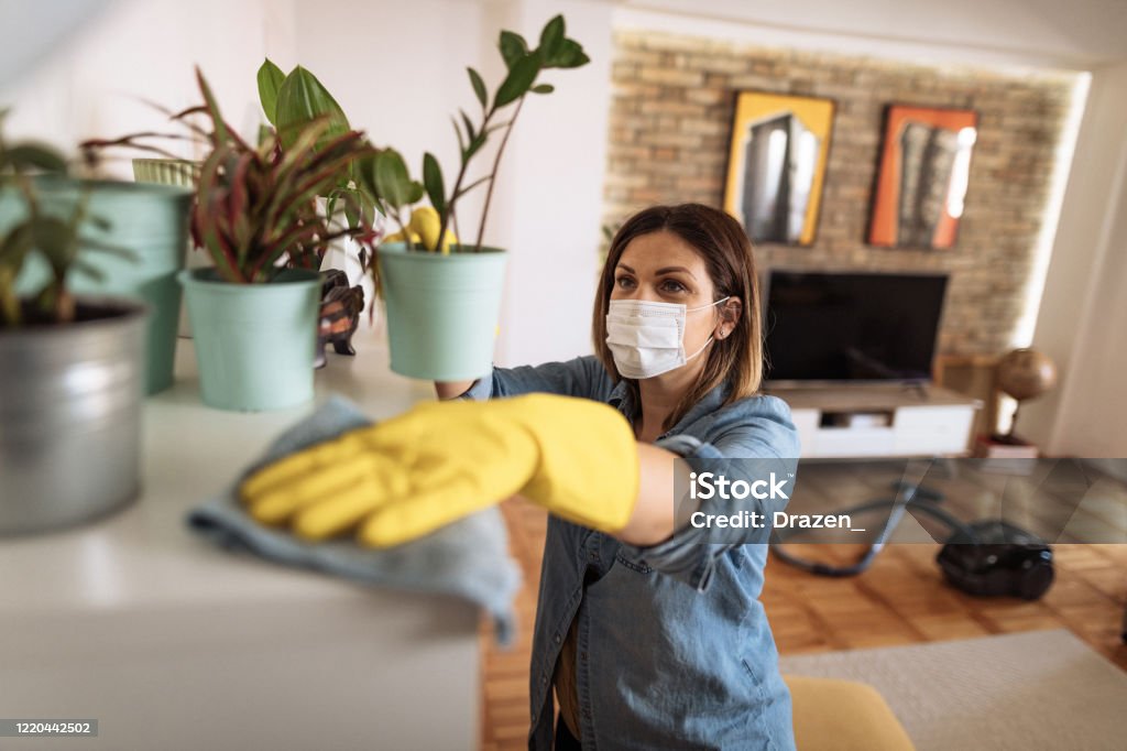 Woman wiping dust from shelf and other furniture in living room Woman working at home, cleaning the floors, washing the laundry and cleaning up the mess in the closet during quarantine Cleaning Stock Photo