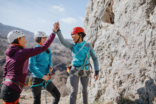 scalatori che danno cinque alti dopo aver terminato con successo la salita - climbing rock climbing women mountain climbing foto e immagini stock