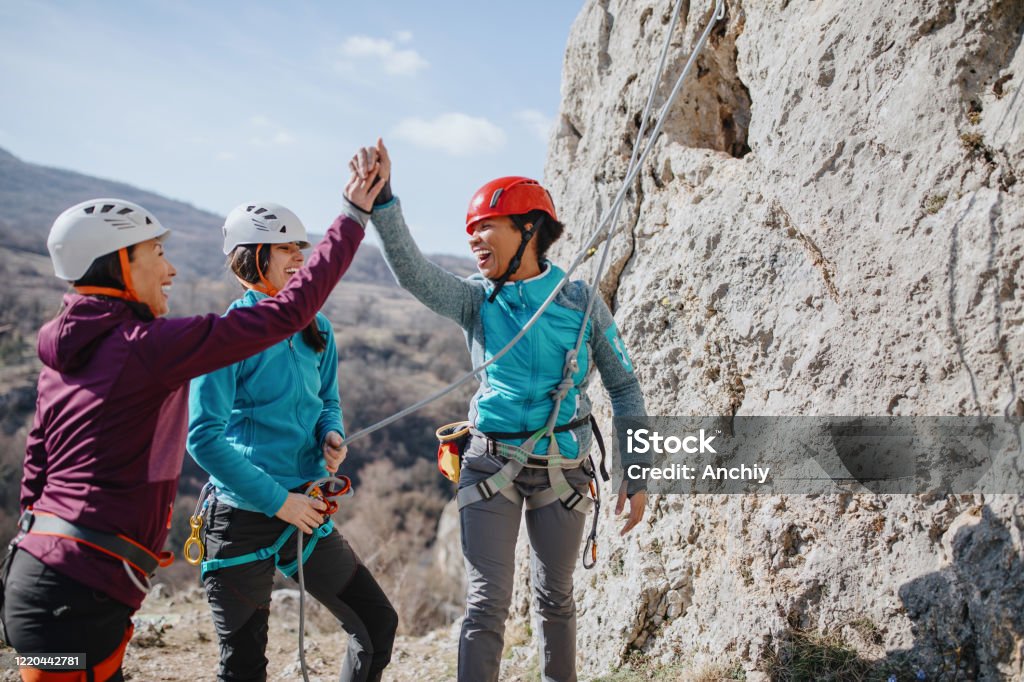 Climbers giving high fives after successfully finishing climb Women Stock Photo