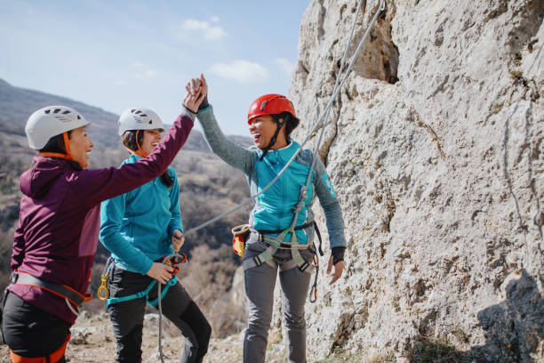 Climbers giving high fives after successfully finishing climb Climbers giving high fives after successfully finishing climb rock climbing stock pictures, royalty-free photos & images
