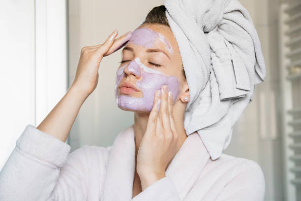 portrait of young beautiful woman with a facial mask having a spa treatment at home - face mask imagens e fotografias de stock