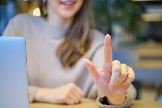 Girl with a laptop at the table abstractly presses a finger. Close up.