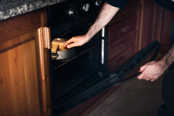istock Quarantine cooking: a man is toasting bread in the oven 1220445990