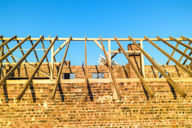 istock Unfinished brick house with wooden roof structure under construction. 1220446543