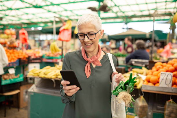 старшая женщина, ходить по магазинам на фермерском рынке - women telephone senior adult on the phone стоковые фото и изображения