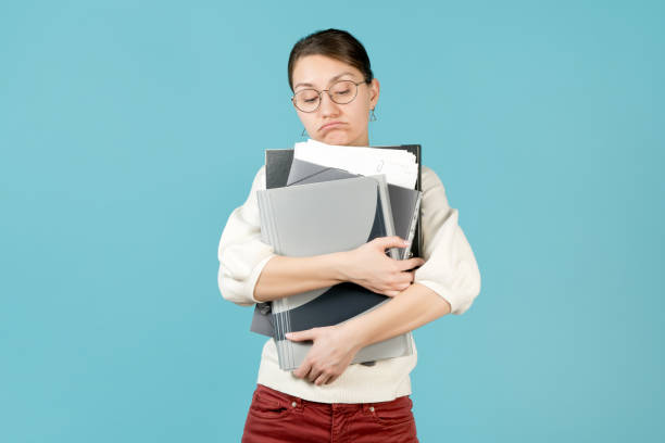 istock A sad girl holds a bunch of documents in her arms 1220457809