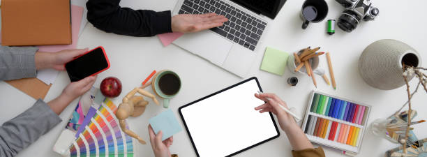 istock Top view of designer team working together in minimal workspace with mock-up tablet, smartphone, laptop and designer supplies 1220474328