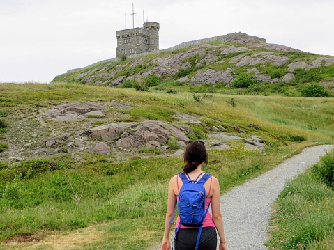 A young female tourist walking up signal hill towards cabot tower.  A famous landmark in St. Johns, Newfoundland, Canada