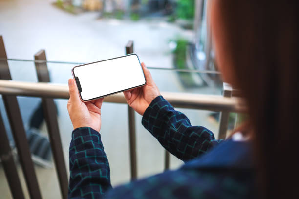 istock a woman holding mobile phone with blank white screen indoors 1220480646