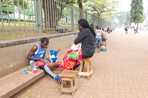 Kampala, Uganda - January 26th, 2020: Unidentified woman gets a pedicure on a street of Kampala, Uganda. All kinds of beauty services are accessible in Kampala city.