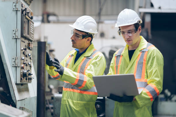 istock technician engineer and mentor checking process on laptop to automated CNC in factory 1220482540