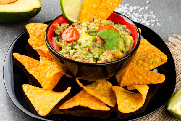 istock Guacamole with corn chips on a white stone background. Fast food 1220483727