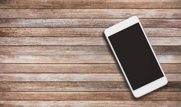 istock Mobile phone is on a wooden plank floor with copy space for your text or image. 1220487180