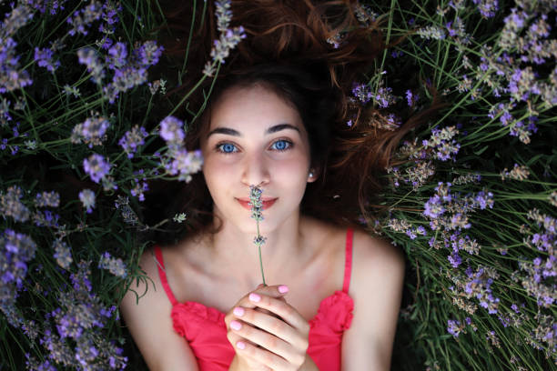 Beautiful young girl with blue eyes laying in lavander field