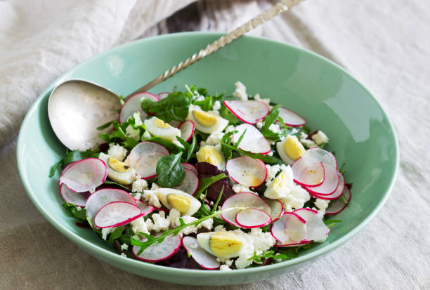 Vegetarian salad with herbs, radish, eggs and cottage cheese on a light background.