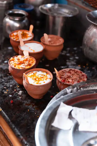 Photo of Indian popular drink Lassi (traditional Dahi yogurt-based drink) in clay cup with various topping on the street in Varanasi.