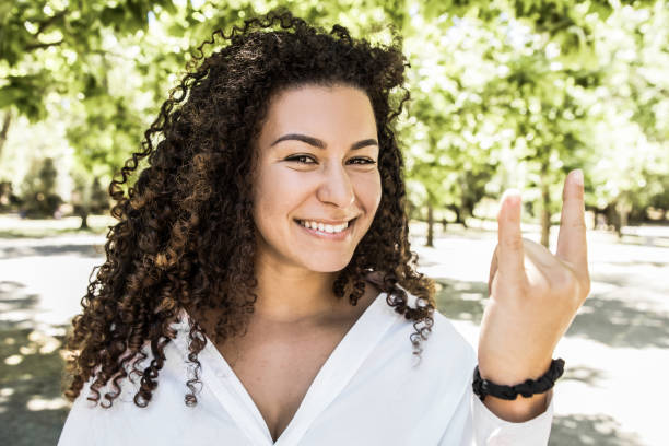 istock Beautiful smiling curly woman showing devil horns sign 1220496199