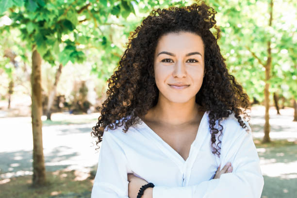 istock Smiling curly woman with crossed arms looking at camera 1220496368