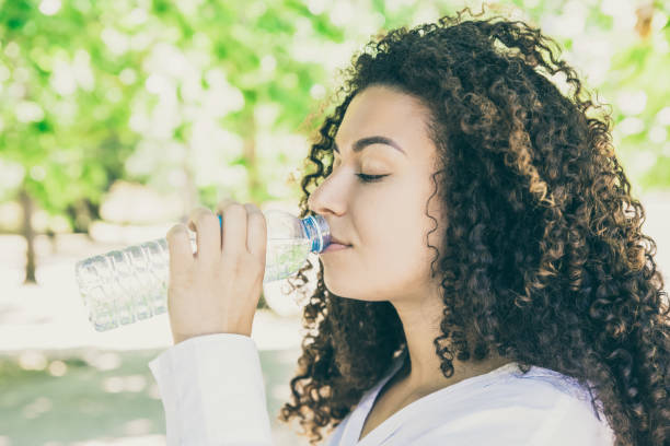 istock Beautiful curly woman drinking water 1220496552